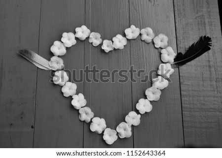 White Sampaguita Jasmine flowersare heart - shaped arrangement ,on blue wooden background, black and white.