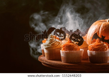 cupcake and pumpkin on a dark background. sweets for the celebration of Halloween.