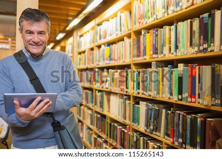 Man smiling while holding tablet pc in the library