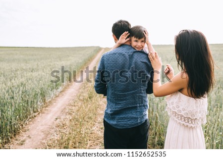 mother and son waving hands on path in field
