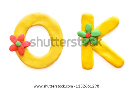 Word OK made of multi-colored plasticine children's English alphabet letters with flowers, isolate on white background
