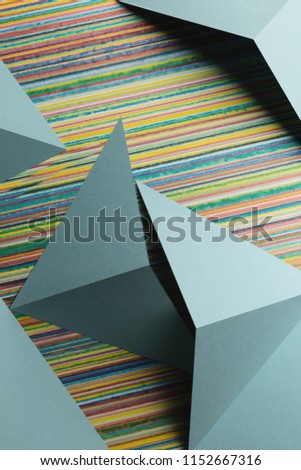 Macro image with triangular shapes of light blue paper, colorful and smudged lines on background