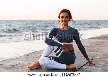 Picture of happy cheerful young fitness woman outdoors in the beach looking camera.