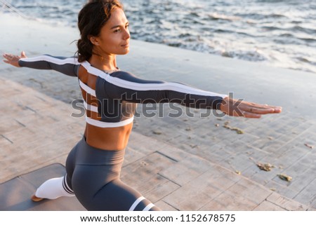 Picture of young fitness lady outdoors in the beach make yoga stretching exercises.