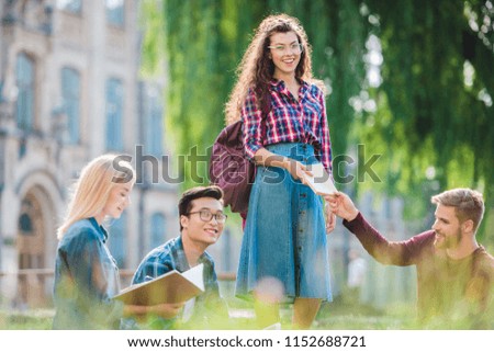 multiracial students studying in park with university on background
