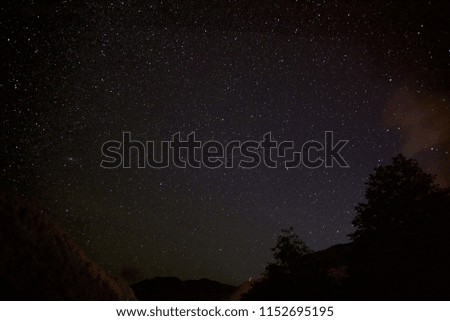 Clear starry night sky with milky way over a mountain river. Bright multicolored stars overhead. Huge space.