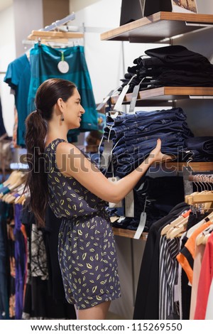 Woman putting jeans on shelf in slothing store