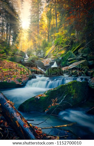 Autumn beauty. Beautiful wild landscape during the fall. Small refreshing stream surrounded with big rocks and colourful trees.
