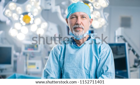 Portrait of the Professional Surgeon Looking Into Camera and Smiling after Successful Operation. In the Background Modern Hospital Operating Room. Royalty-Free Stock Photo #1152711401