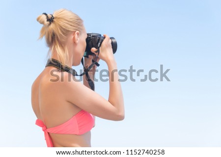A female photographer in a swimsuit makes a photo on the sea, the ocean. Beach vacation, travel.