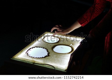 Sand animation. Hands girls draw sand. Paint an illustration with sand on light table by finger. Art therapy