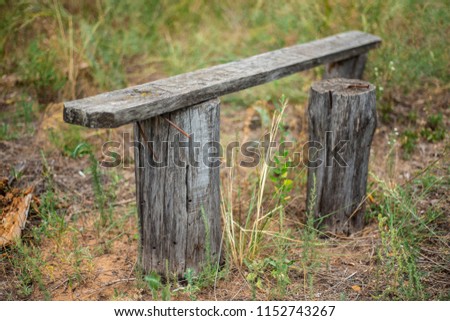 Old wooden bench of logs in an abandoned green area