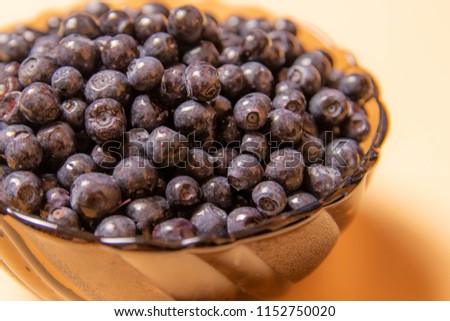blueberries in a glass plate on an orange background
