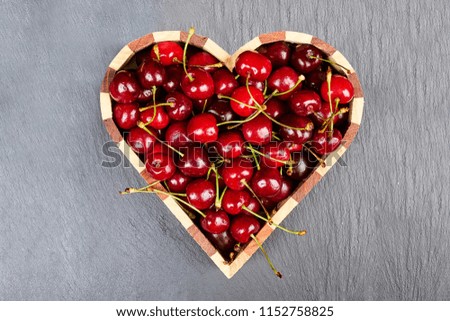 Ripe, fresh cherries or heart-shaped cherries on a dark background.