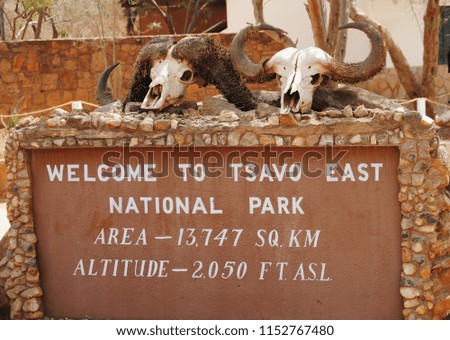Picture of the Tsvavo national park sign in kenya. With two skulls on top.