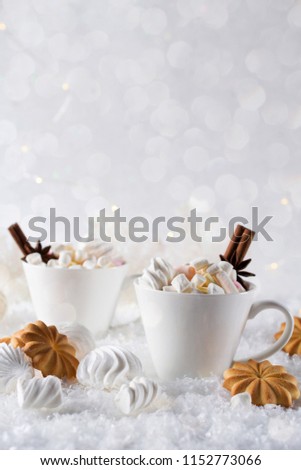 Blurred background of winter frost and Christmas chocolate spice beverage with cookies in white cups
