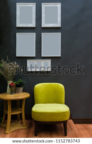Modern yellow fabric chair and white wooden picture frame on black wall interior decoration