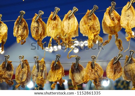 Grilled squids hanging sell in street night market, street foods
