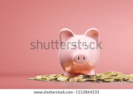 Pink piggy bank and coins on desk