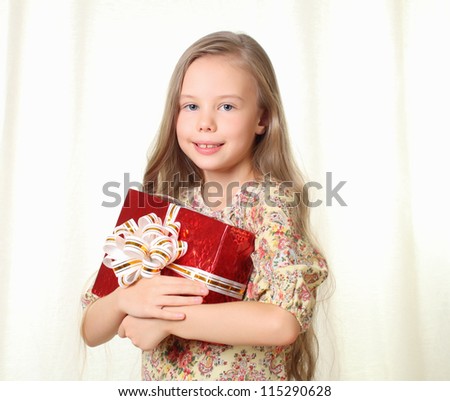Little blond girl holding a red glamorous gift