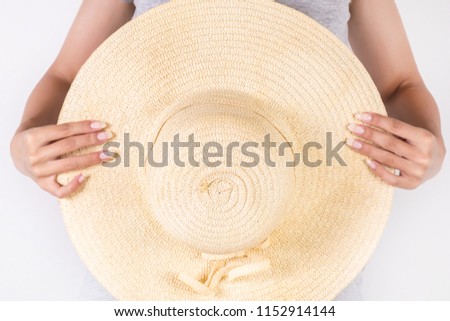 Beautiful young woman holding big straw hat in hand isolated on white background. Summer concept clothes. Close up, selective focus