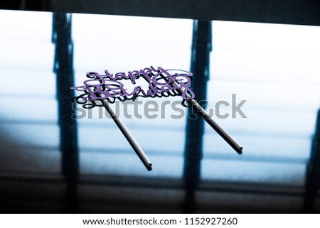 Hand Holding Purple Happy Birthday word over black background