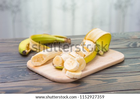 On a wooden dark table lie yellow natural banana freshly cutted and peeled. Banana 3 comb on wooden floor. Diet. Minimalist, organic and vegetarian photo of banana.