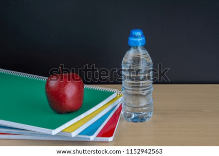 red apple on books with pencils and empty blackboard , back to school