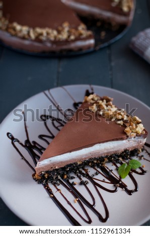 Slice of chocolate cheesecake with walnuts on dark background