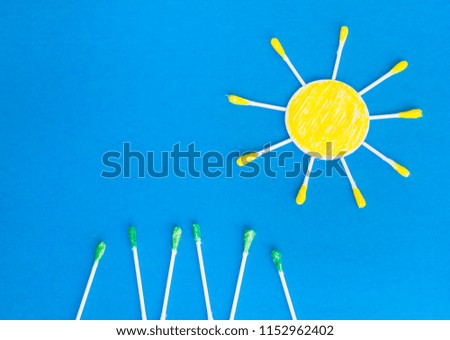Cotton pad and sticks in the shape of sun on the blue background, morning beauty routine concept. 