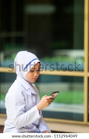 Medical staff or Nurse checking on her mobile phone and smiling