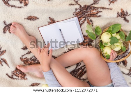 girl on a picnic on the nature rests on a blanket of blankets, drinks tea, eats apples, dreams and thinks, the concept of a lifestyle in the style of a lagom, flat lay top view the foot