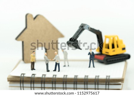 Miniature people: Businessman handshake on book and wood house using as background commitment, agreement and partnership concept