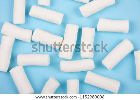 Pile of white marshmallows on a pastel blue background (top view)