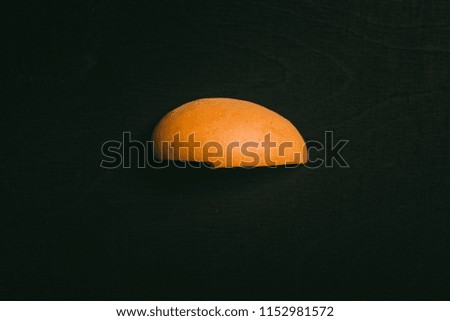 Cut peach with seed lying on black chalkboard in background with copy space from above as flat lay