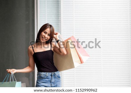 A woman is shopping happily in her, with a variety of colored bags bought from the store. She smiles because she's glad to have bought a discounted item.