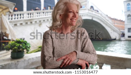 Happy smiling woman on cafe patio overlooking Venice canal on vacation in Italy