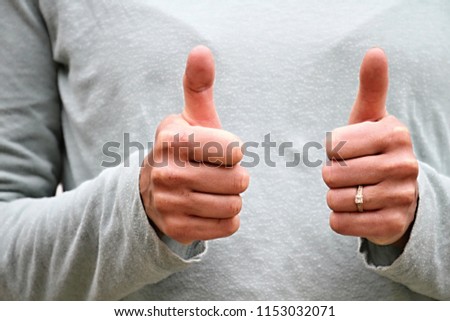 woman with thumbs up gesture on grey background stock photo