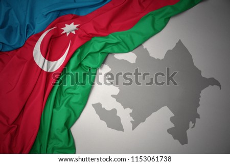 waving colorful national flag of azerbaijan on a gray map background.