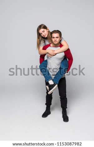 Love forever. Young brunete handsome boyfriend is piggy backing his cute lover, wearing casual clothes, on white background