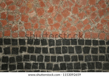 Close up indoor view of an ancient floor made of red and black mosaics. Pattern of small ceramic squares. Old surface divided in two colors. Abstract design with lines and angles. Vintage picture.