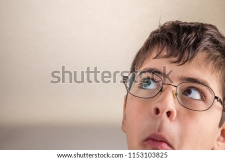 Boy looking upwards at his side sucks cheeks and  squeezes his lips making weird face as a sign of surprise