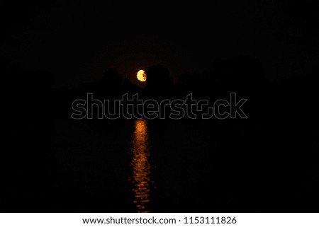 Soft focus of beautiful bright red - orange moon on dark blue sky during twilight time after sunset