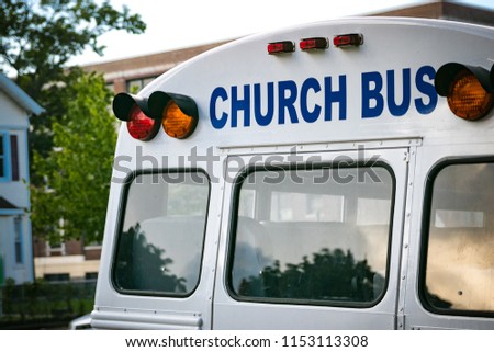 "CHURCH BUS" wording on back of a white school bus.