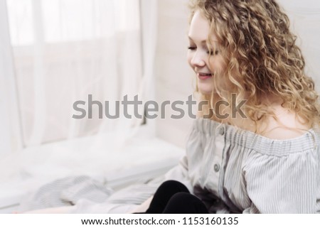 beautiful curly young woman resting and relaxing at home, good mood, smiling
