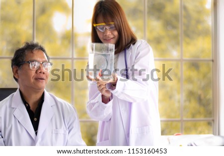 Young woman and man scientist brainstorm and discuss about fish (siamese fighting fish and golden fish) disease in the marine lab as teamwork with the blurred background of yellow tree in autumn