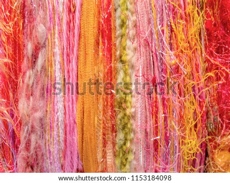 Vertical striped background composed of varying colors and textures of yarns, creating color sequences from left to right.
