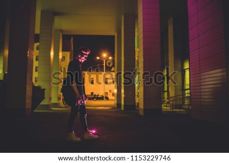 Young red haired man on black night background. lights of the night city. on the model falls the light from outdoor advertising