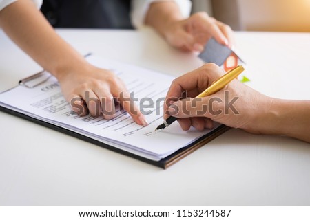 Estate agent pointing finger on document showing where to sign. Signing a paper document for buying house.Real estate, home loan and insurance concept Royalty-Free Stock Photo #1153244587