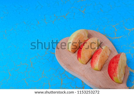 Apples on a board on a turquoise background. Cut red and green apples. Turquoise color. Free space for text.